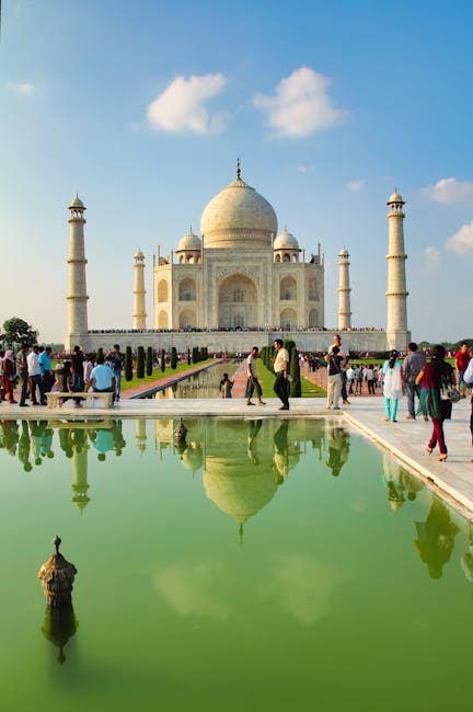 The iconic Taj Mahal with its reflection in a pool, surrounded by tourists in Agra, India.
